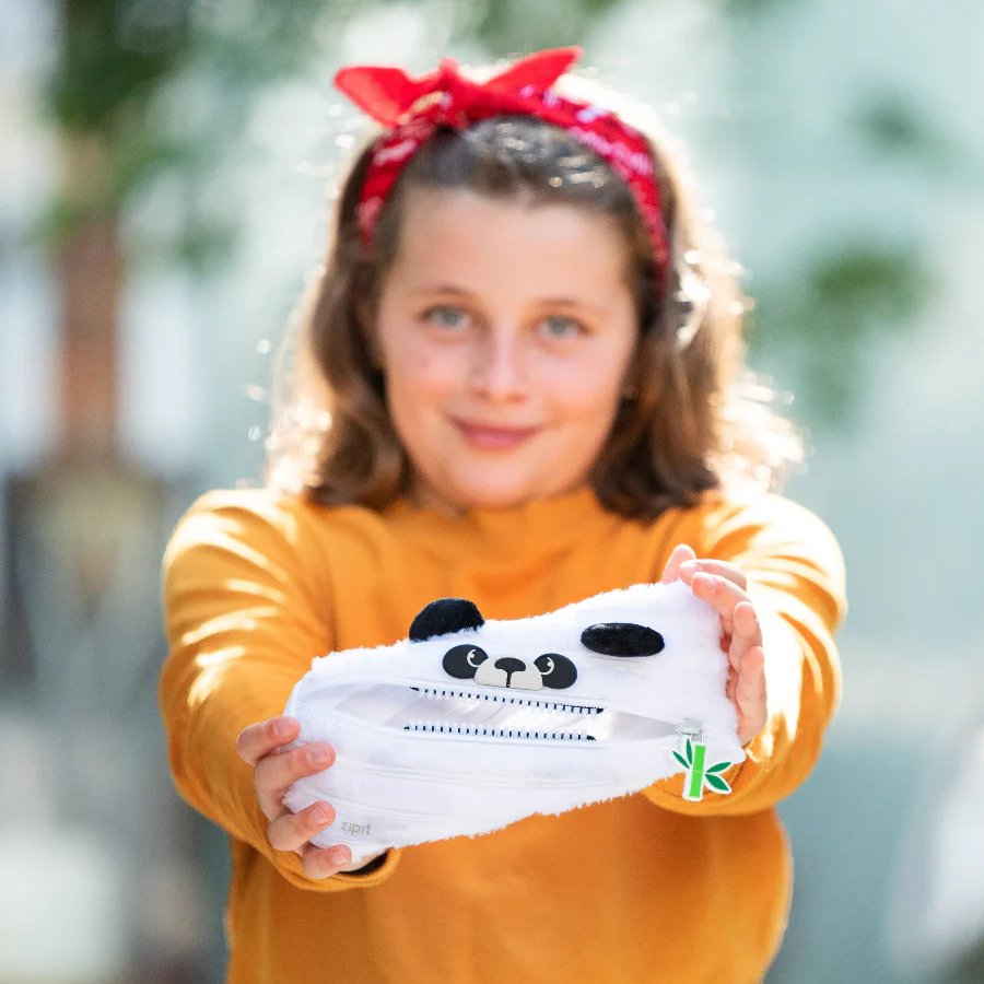 Child holding a white product with panda design outdoors
