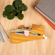 Yellow pencil case with cartoon face on a wooden surface with stationery items.