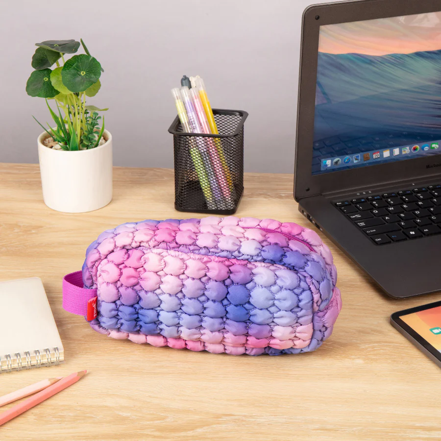 Colorful pencil case on a desk with laptop, tablet, and stationery items.