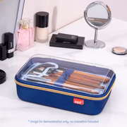 Blue cosmetic case with makeup brushes on a vanity table with mirror and products.