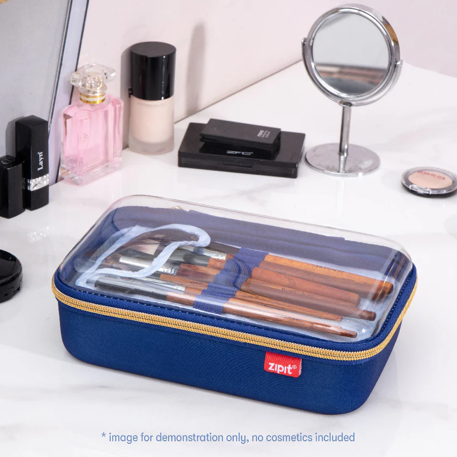 Blue cosmetic case with makeup brushes on a vanity table with mirror and products.